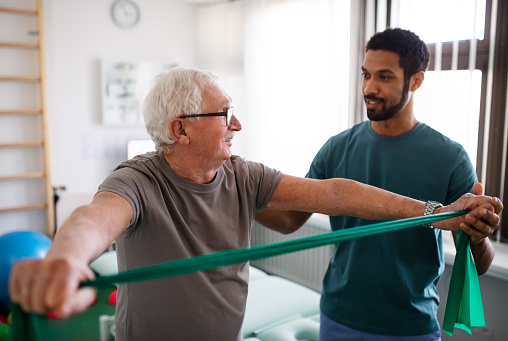 A young physiotherapist exercising with senior patient